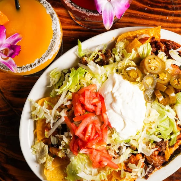 El Mezcal Mexican Restaurant's nachos with beef, lettuce, tomatoes, jalapeños, and sour cream, with a drink.