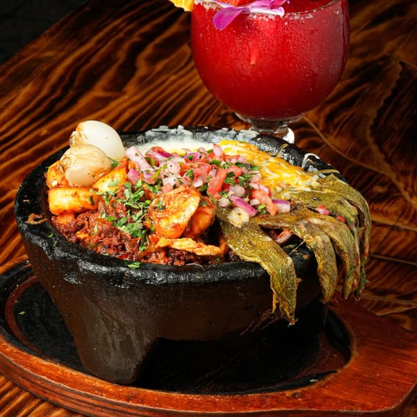 El Mezcal's molcajete with meat, shrimp, cheese, peppers, and pico de gallo, with a red margarita.